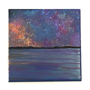 Puede incluir: Una pintura de un cielo nocturno estrellado sobre un cuerpo de agua azul oscuro. El cielo est&aacute; lleno de estrellas blancas y una nube giratoria de naranja, rosa y morado.