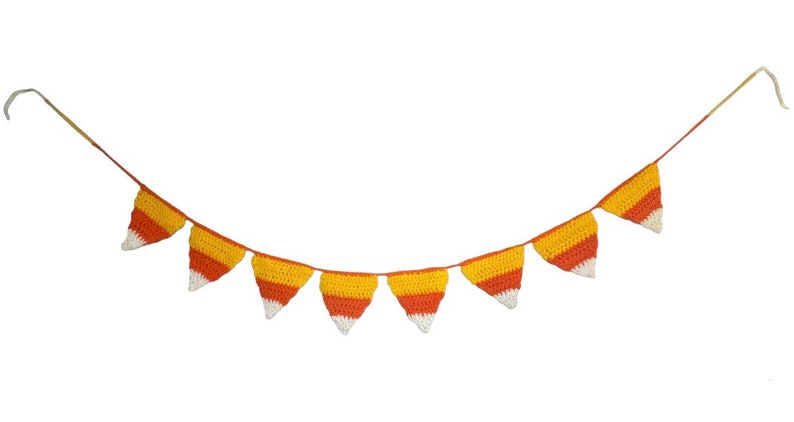 May include: A crocheted garland featuring candy corn-shaped pennants. Each pennant has a white tip, a yellow center, and an orange base. The garland is strung on a thin, tan cord, perfect for Halloween or fall decor.