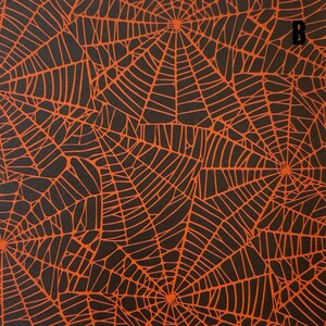 K&ouml;nnte beinhalten: Eine schwarze Stoff- oder Papieroberfl&auml;che mit einem sich wiederholenden Muster aus orangefarbenen Spinnennetzen. Das Design besteht aus mehreren miteinander verbundenen Netzstrukturen mit feinen Linien. Der Buchstabe B ist oben rechts.