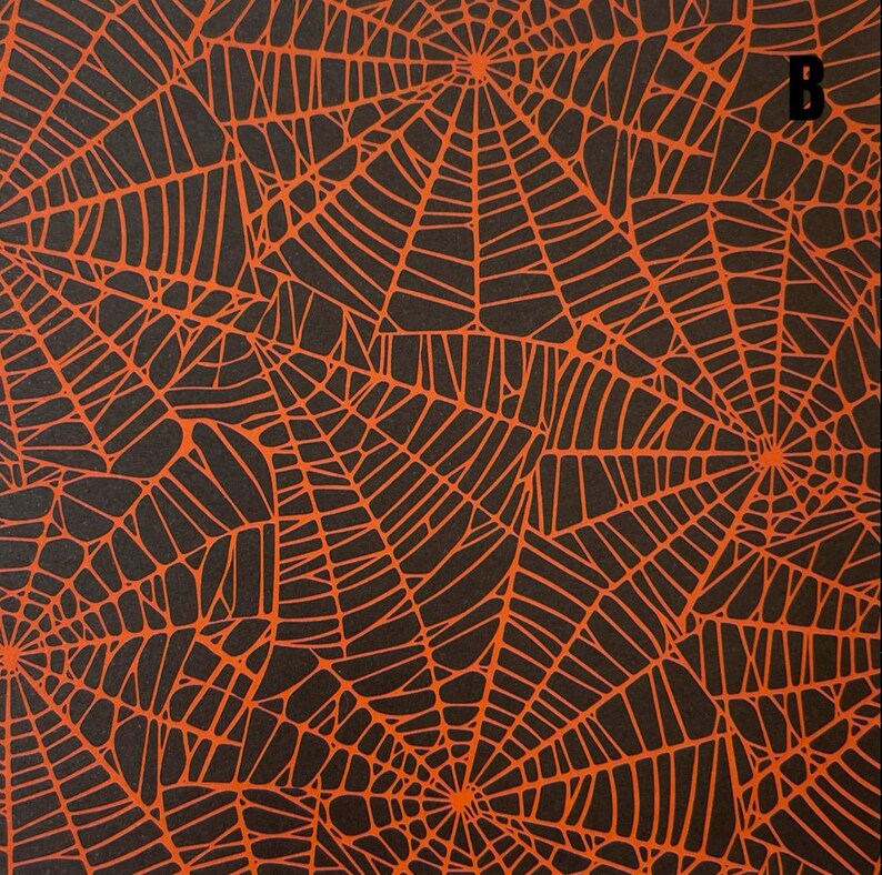 K&ouml;nnte beinhalten: Eine schwarze Stoff- oder Papieroberfl&auml;che mit einem sich wiederholenden Muster aus orangefarbenen Spinnennetzen. Das Design besteht aus mehreren miteinander verbundenen Netzstrukturen mit feinen Linien. Der Buchstabe B ist oben rechts.