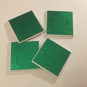 May include: Four square green glitter coasters with white borders.