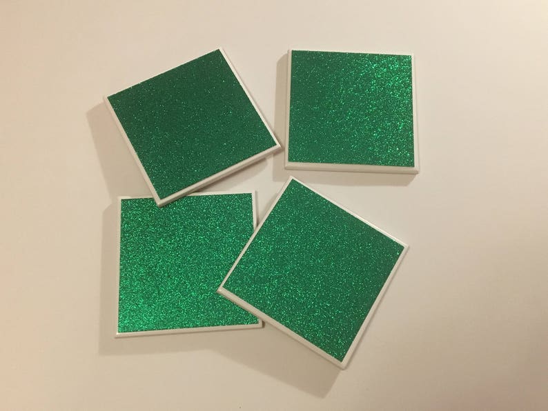 May include: Four square green glitter coasters with white borders.