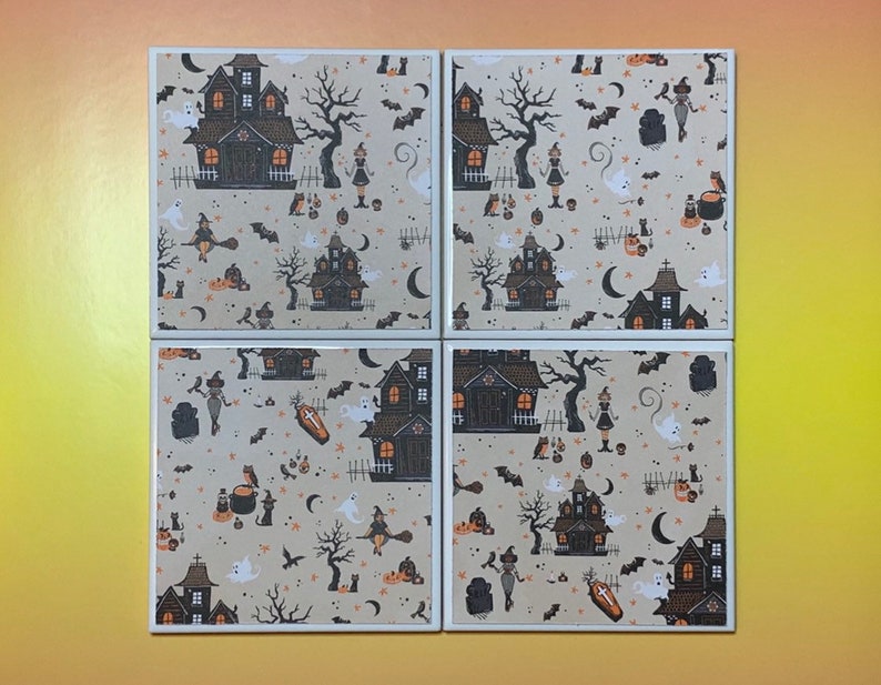 Pu&ograve; includere: Un set di quattro sottobicchieri quadrati in ceramica con un motivo ripetuto su sfondo beige. Il design include case infestate nere, zucche arancioni, fantasmi bianchi, gatti neri, pipistrelli, lune crescenti e streghe su manici di scopa.