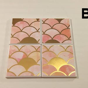 K&ouml;nnte beinhalten: Set mit vier Untersetzern in Rosa und Gold mit geometrischem Muster. Die Untersetzer zeigen ein sich wiederholendes Muster aus &uuml;berlappenden Halbkreisen in einem hellrosa und goldenen Farbschema.