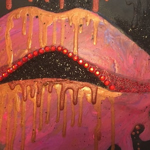 May include: A painting of lips featuring a pink and metallic gold color palette with paint dripping effects. The upper lip is lined with a row of small, bright red circular rhinestones, and the entire composition is set against a black background.