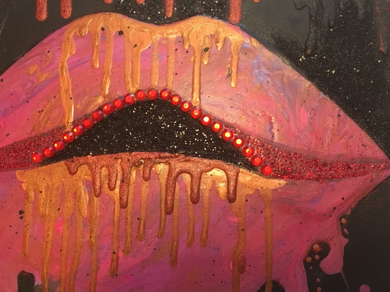 May include: A painting of lips featuring a pink and metallic gold color palette with paint dripping effects. The upper lip is lined with a row of small, bright red circular rhinestones, and the entire composition is set against a black background.