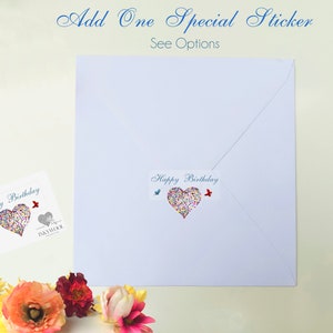 May include: A white envelope and card with a heart-shaped design made of colorful confetti. The card and envelope have the words "Happy Birthday" printed on them. The image also includes the text "Add One Special Sticker See Options".