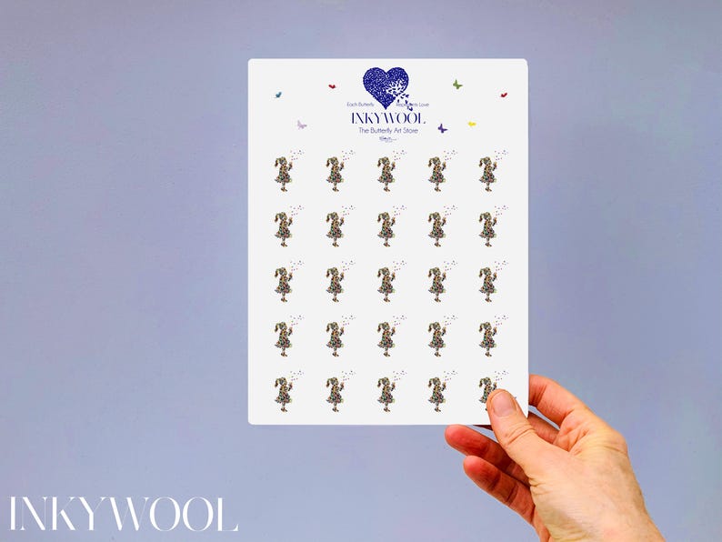 May include: A white rectangular card featuring multiple illustrations of a girl in a leopard print dress, holding a wand. The card has a blue heart logo with the text "INKYWOOL" and "The Butterfly Art Store". The card is held by a hand.