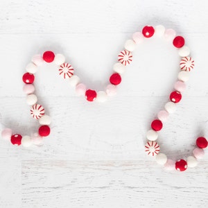 May include: A red and white felt garland with candy cane and polka dot designs. The garland is strung on white twine and is perfect for decorating for the holidays.