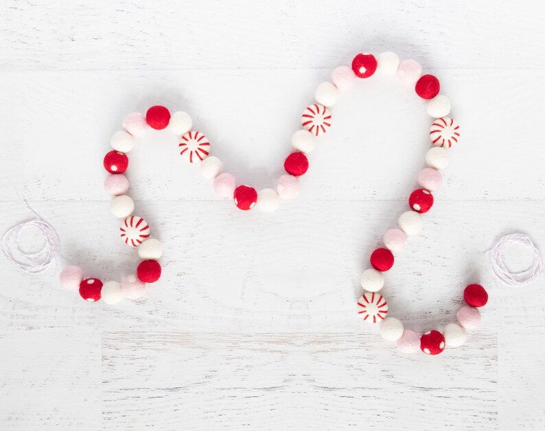 May include: A red and white felt garland with candy cane and polka dot designs. The garland is strung on white twine and is perfect for decorating for the holidays.