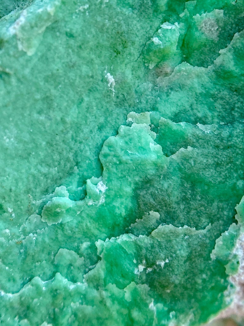 May include: Close-up of a green, textured stone with a rough surface. The stone has a mottled appearance with shades of light and dark green.