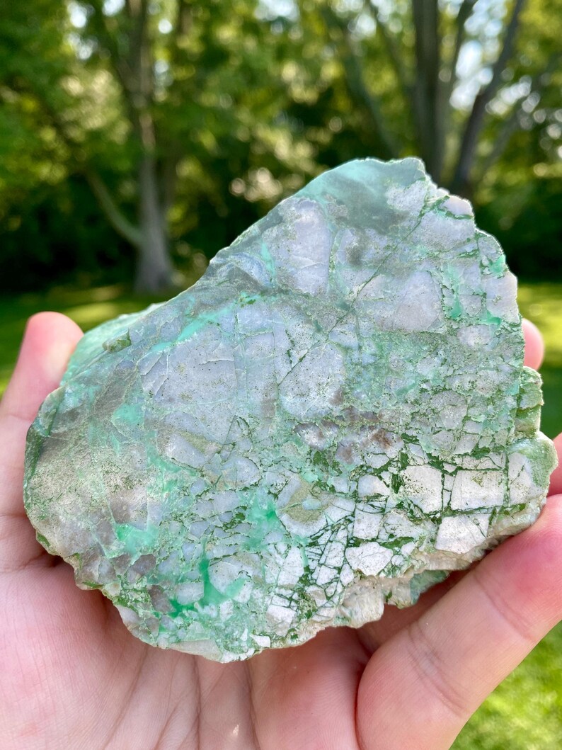 May include: A large, rough, green and white, natural stone with a unique, marbled pattern.
