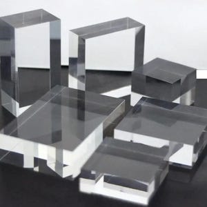 May include: Five clear acrylic display stands of various sizes. The stands are rectangular and square in shape, with smooth edges and a polished finish.