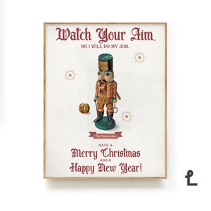 May include: Wooden framed print featuring a vintage nutcracker illustration. The artwork includes the text "Watch Your Aim" and "Merry Christmas and a Happy New Year!" in burgundy script, with star accents.