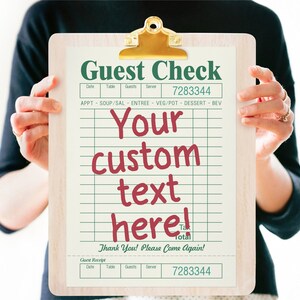 May include: A white guest check clipboard with green and red text. The text reads "Guest Check", "Your custom text here!" and "Thank You! Please Come Again!" The clipboard has a gold clip and a white background with green lines.