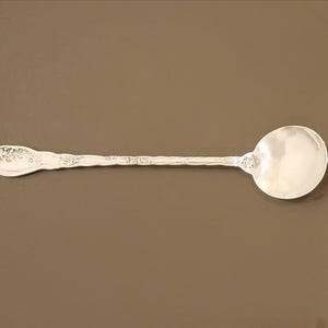 May include: A silver serving spoon with an ornate handle and a round bowl.