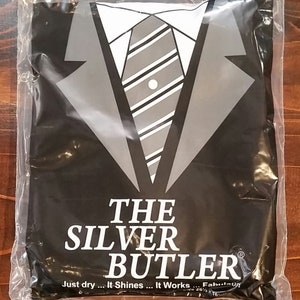 May include: A black plastic bag with a white and gray tuxedo design and the text "THE SILVER BUTLER" in white. The text "Just dry... It Shines... It Works... Fab..." is also visible in white.
