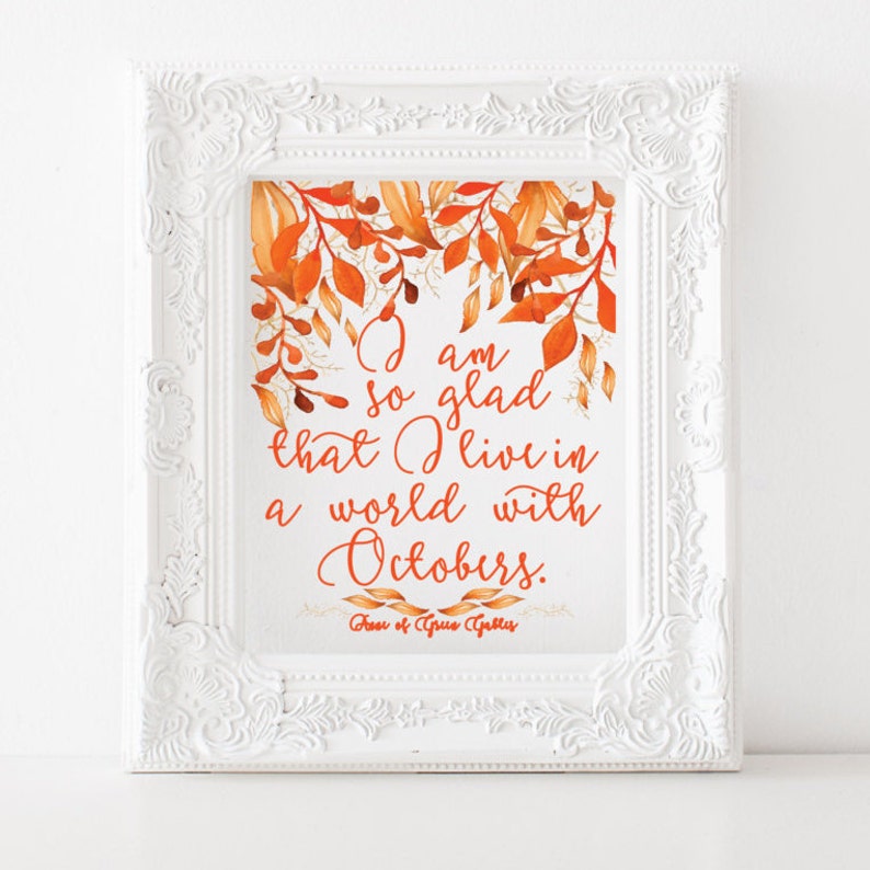 May include: A white framed print with a watercolour illustration of autumn leaves in shades of orange and gold. The print features the quote "I am so glad that I live in a world with Octobers." by the author "Her of Gsus Gubles".