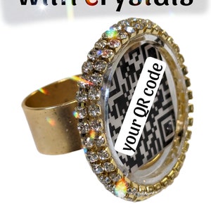 May include: A gold ring with a clear round bezel set with rhinestones. The bezel contains a black and white QR code with the text "your QR code" printed on it.