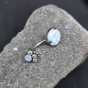 May include: A silver belly button ring with a white opal and clear crystal accents.