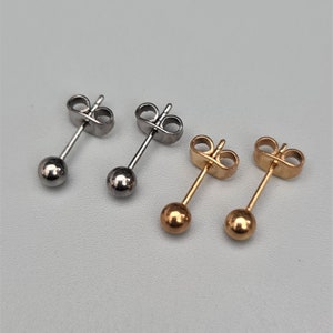 May include: Three pairs of stud earrings, one pair is silver, one pair is gold, and one pair is a mix of silver and gold.