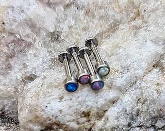 May include: Five silver barbell earrings with opal gemstones. The gemstones are in shades of blue, purple, and white.