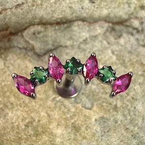 Op de afbeelding: Een zilverkleurig lichaamsjuweel met een gebogen ontwerp, met afwisselend roze en groene marquise-geslepen edelstenen. De edelstenen zijn in een rij gerangschikt, wat een decoratieve uitstraling creëert. De sieraden zijn ontworpen voor body piercing.