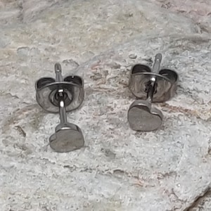 May include: A pair of silver heart-shaped stud earrings. The earrings have a post and butterfly backing.
