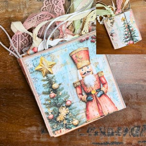 May include: A decorative Christmas-themed journal with a vintage aesthetic. The cover features a nutcracker soldier and a Christmas tree with ornaments. The journal is adorned with a gold star and various ribbons and lace.