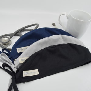 May include: A set of three ceramic mugs with a speckled, matte finish. The mugs are in shades of cream, light gray, and dark gray. Each mug has a simple, minimalist design, perfect for coffee or tea.