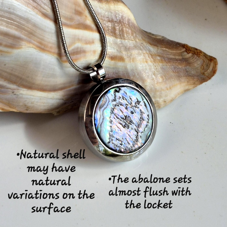 May include: A round silver-toned locket pendant featuring an iridescent abalone shell inlay on a thin snake chain. Text reads: Natural shell may have natural variations on the surface. The abalone sets almost flush with the locket.