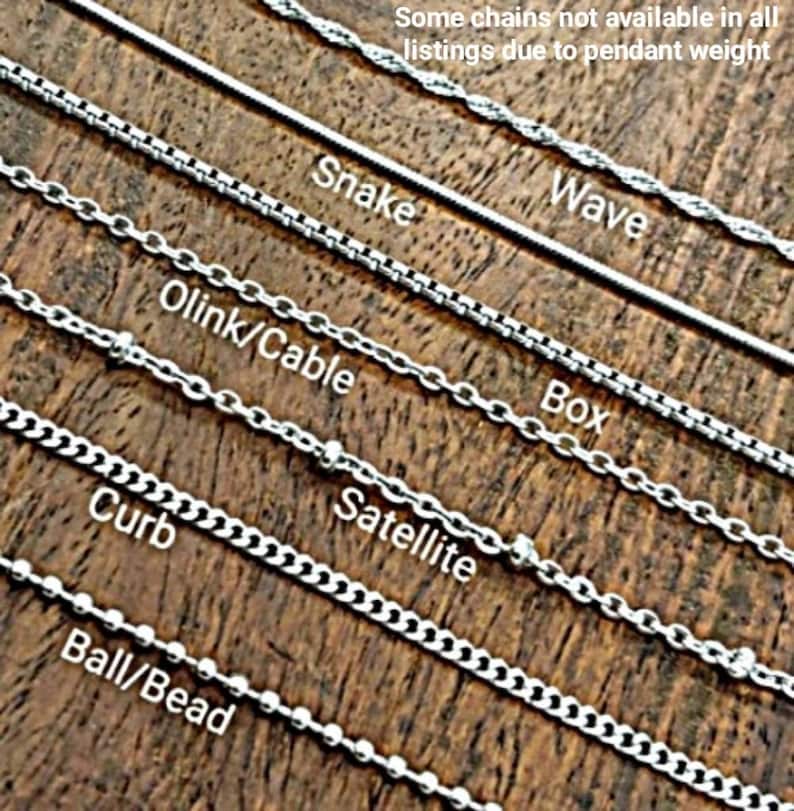Peut inclure: Plusieurs mod&egrave;les de cha&icirc;nes argent&eacute;es, dont Snake, Wave, Box, Olink/Cable, Satellite, Curb et Ball/Bead. Le texte "Some chains not available in all listings due to pendant weight" est &eacute;galement pr&eacute;sent.