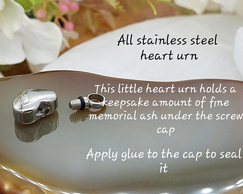May include: A polished stainless steel heart-shaped urn with a detachable screw cap. The text reads: All stainless steel heart urn. This little heart urn holds a keepsake amount of fine memorial ash under the screw cap. Apply glue to the cap to seal it.