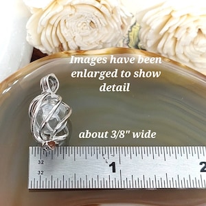 Puede incluir: Un colgante de cristal transparente, de aproximadamente 1 cm de ancho, encerrado en una jaula de alambre plateado. La imagen incluye el texto "Images have been enlarged to show detail" y "about 3/8" wide."