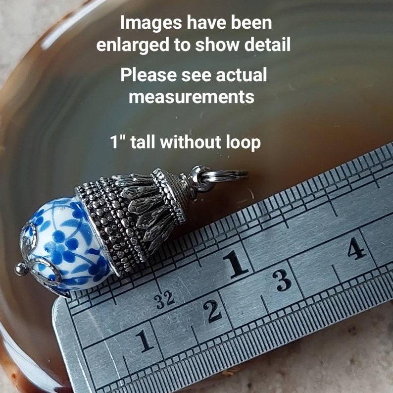 Puede incluir: Un charm de plata con una cuenta de porcelana azul y blanca y una parte superior decorativa. El charm mide 2,5 cm de alto sin el bucle. Las im&aacute;genes se han ampliado para mostrar los detalles. Consulte las medidas reales.