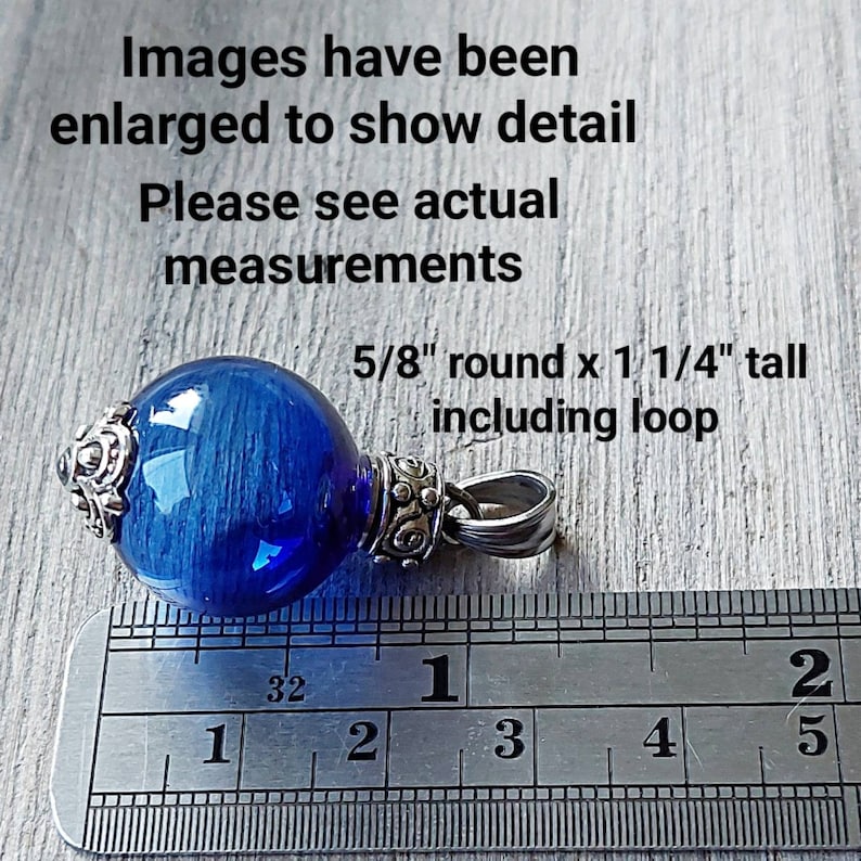 May include: A blue glass pendant with silver-colored metal accents. The pendant is round, measuring 5/8" in diameter and 1 1/4" tall including the loop. The image includes text that says "Images have been enlarged to show detail. Please see actual measurements."