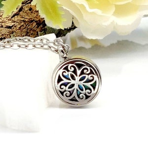May include: Silver necklace with a round pendant featuring a delicate, intricate floral design. The pendant has an openwork pattern, revealing a colorful iridescent background.