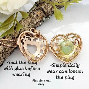 Pu&ograve; includere: Un medaglione a forma di cuore color oro con un design a filigrana aperta contenente una piccola fiala di vetro con un liquido verde chiaro. Il testo recita: Seal the plug with glue before wearing, Simple daily wear can loosen the plug, Plug style may vary.