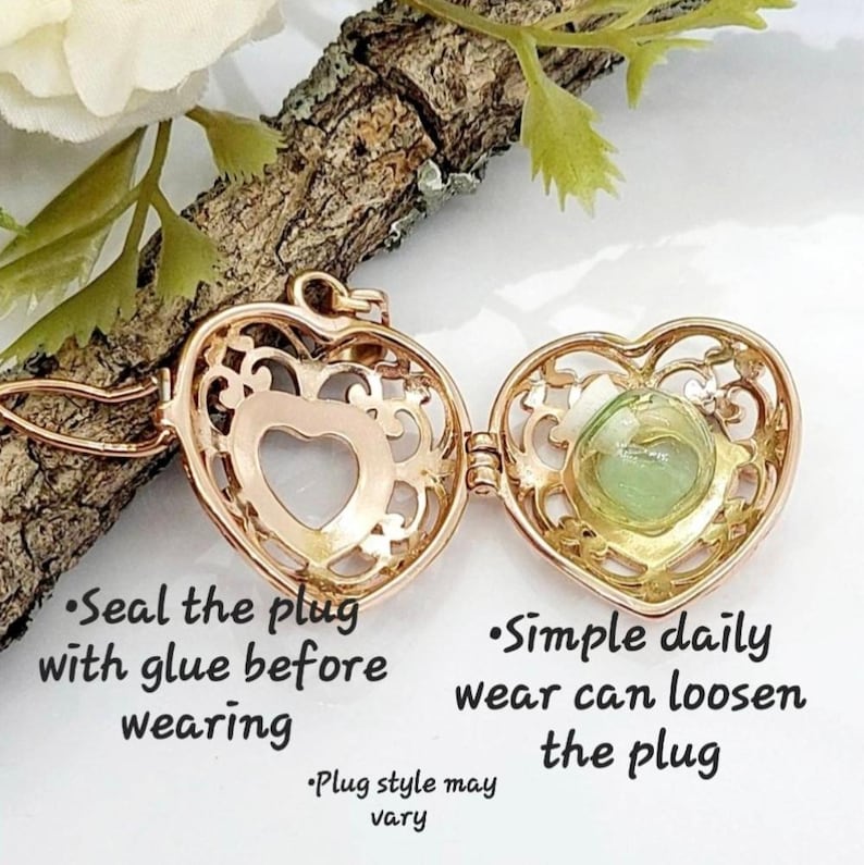 Pu&ograve; includere: Un medaglione a forma di cuore color oro con un design a filigrana aperta contenente una piccola fiala di vetro con un liquido verde chiaro. Il testo recita: Seal the plug with glue before wearing, Simple daily wear can loosen the plug, Plug style may vary.