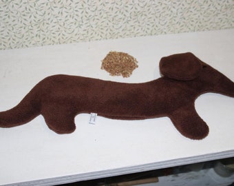 May include: A brown plush dachshund-shaped heating pad filled with brown grains.