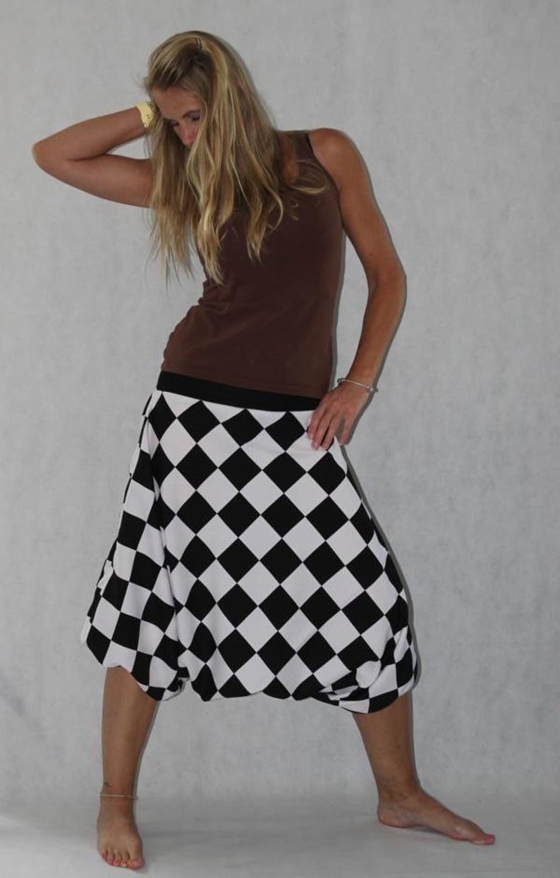 May include: A woman wearing a brown tank top and a black and white checkered skirt. The skirt is a loose-fitting, flowy style.