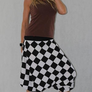 May include: A woman wearing a brown tank top and a black and white checkered skirt. The skirt is a loose-fitting, flowy style.