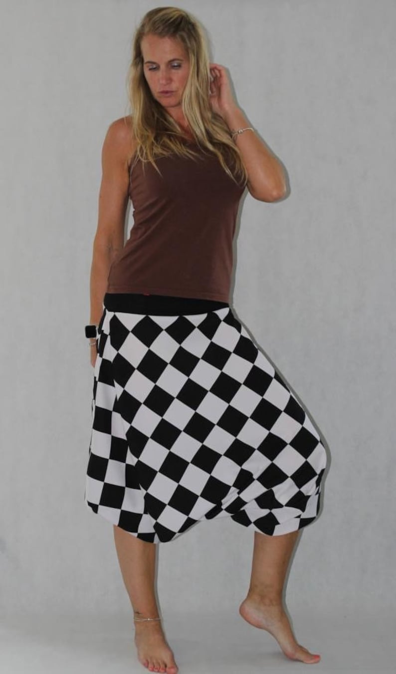 May include: A woman wearing a brown tank top and a black and white checkered skirt. The skirt is a loose-fitting, flowy style.