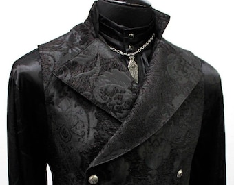 May include: A black brocade vest with a shawl collar and silver buttons. The vest has a floral pattern and is worn over a black shirt.