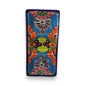 May include: A rectangular ceramic serving dish with a blue background and a colourful floral design. The dish has a raised rim and is perfect for serving appetisers, snacks, or desserts.