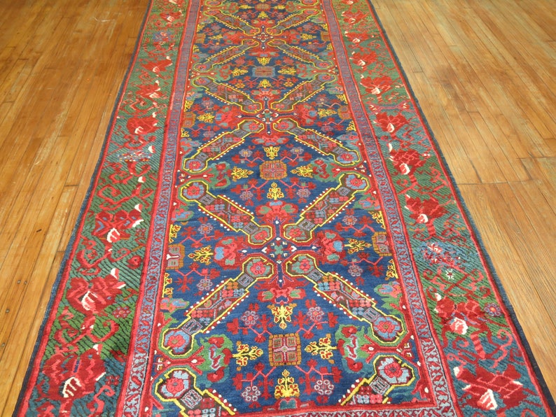 May include: A blue and red patterned rug with a floral design. The rug has a border with a green and red floral pattern.