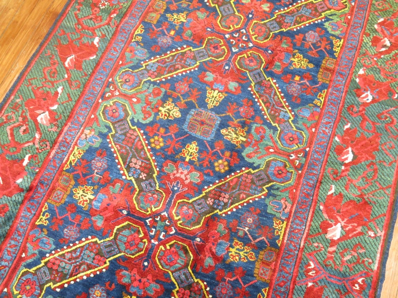 May include: A blue, red, and green patterned rug with a floral design. The rug has a geometric pattern in the center and a border with a floral design.