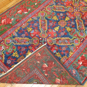 May include: A traditional Persian rug with a blue, red, and green floral pattern. The rug has a fringe border and is folded in half.
