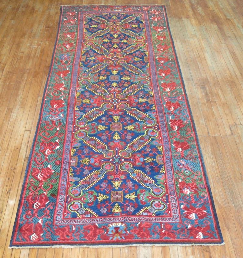 May include: A long, narrow rug with a blue background and a red, green, and yellow geometric pattern. The rug has a fringe border.