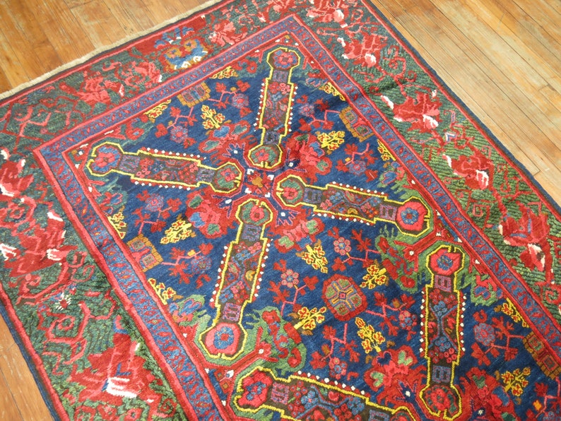 May include: A vintage Persian rug with a deep blue background and intricate floral patterns in shades of red, yellow, and green. The rug has a central medallion and a border with a repeating design.
